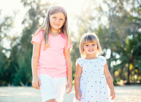 Adorable young sisters, cute little girls together at the beachの写真素材