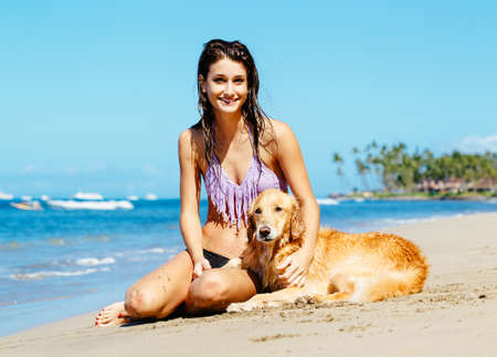 Attractive Young Woman Enjoying Sunny Day at the Beach with her Dog, Golden Retrieverの写真素材