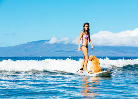 Attractive Young Woman Surfing with her Dog. Riding Wave Together in Ocean. Surfing Dog.の写真素材