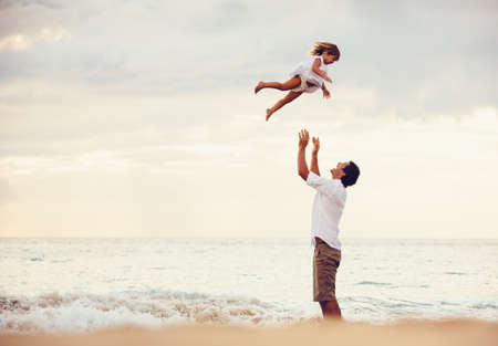 Healthy loving father and daughter playing together at the beach at sunset Happy fun smiling lifestyleの写真素材