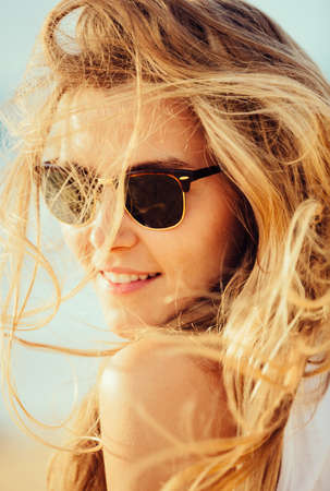 Portrait of the beautiful girl close-up, wind fluttering her hair. Beach fashion lifestyle.の写真素材