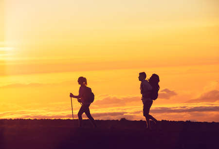 Hikers with backpacks hiking on top of a mountain at sunsetの写真素材