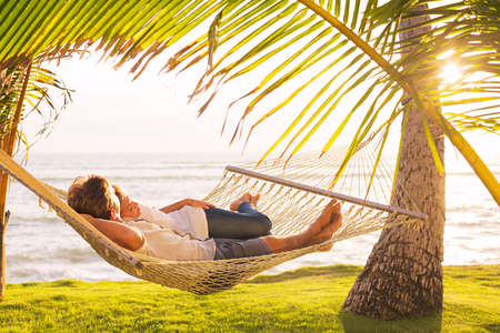 Romantic couple relaxing in tropical hammock at sunsetの写真素材