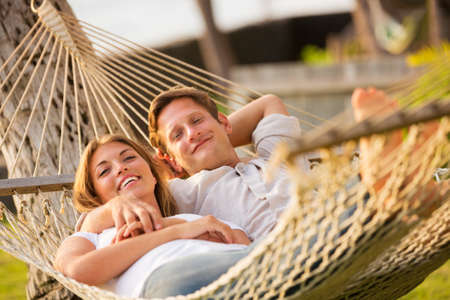 Romantic couple relaxing in tropical hammock at sunsetの写真素材