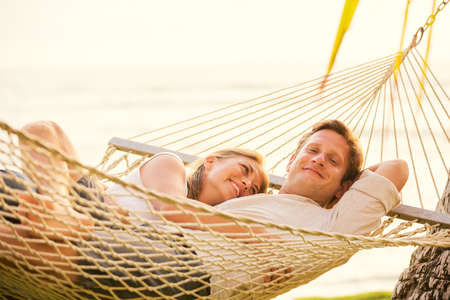 Romantic couple relaxing in tropical hammock at sunsetの写真素材