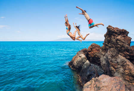 Summer fun, Friends cliff jumping into the ocean. の写真素材