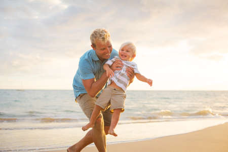 Father and son playing on the beach at sunset