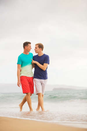 Happy gay couple walking on the beachの写真素材