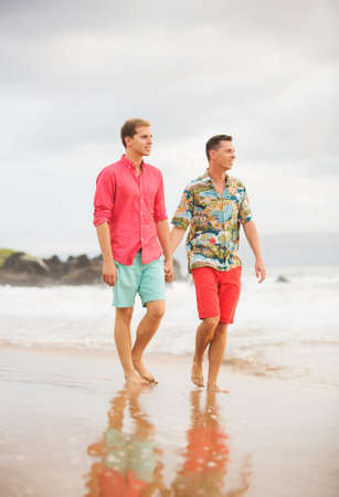 Happy gay couple walking on the beachの写真素材