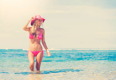 Young fashion woman walking on the tropical beach in bikini, retro style color toneの写真素材