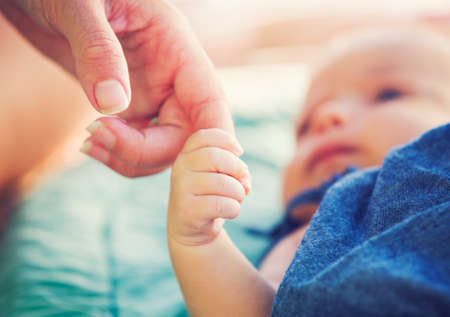 Cute newborn baby holding mother's hand