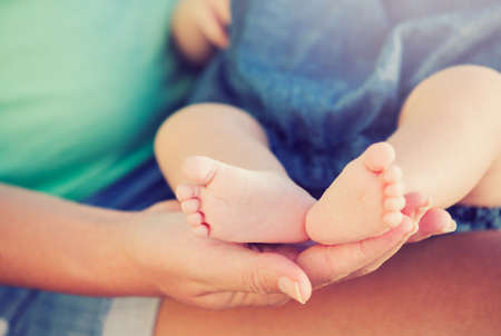 Mother holding adorable newborn baby feetの写真素材