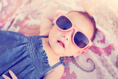Portrait of adorable baby girl wearing sun glasses, vintage style warm color toneの写真素材