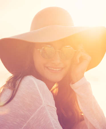 Fashion portrait of beautiful young woman on the beach at sunset, bright warm sunny color tones