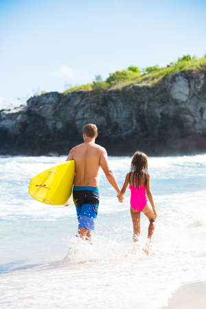 Father and Daughter on the Beach going Surfing Together in Hawaii, Summer Lifestyle Family Conceptの写真素材