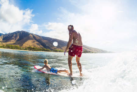 Father and Son Surfing Together. Riding Wave on Surfboard Tandem. Fatherhood, Family Fun Outdoor Lifestyle.の写真素材
