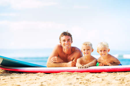 Father and Two Young Sons Going Surfing at the Beachの写真素材