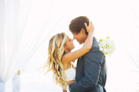 Wedding, Beautiful Romantic Bride and Groom Kissing and Embracing at Sunsetの写真素材