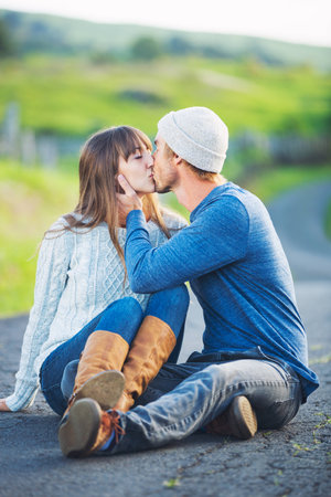 Happy Young Couple Having Fun Outdoors. Romantic Couple Kissing in Love on Country Road.の写真素材