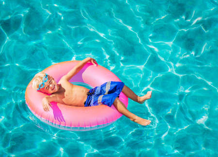 Happy Young Boy Floating in Swimming Pool on Raft
