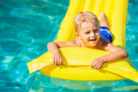 Young Boy Relaxing and Having Fun in Swimming Pool on Yellow Raft. Summer Vacation Fun. Relaxing...