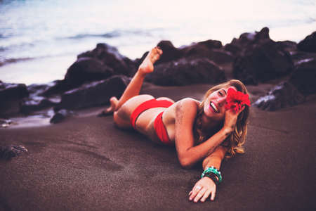 Beautiful Woman Relaxing on Tropical Beach at Sunsetの写真素材
