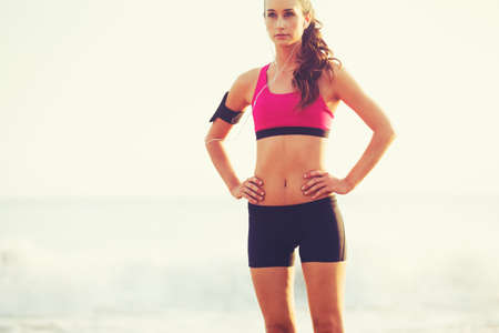 Healthy Active Lifestyle. Young sports fitness woman on the beach at sunset ready for workout.の写真素材