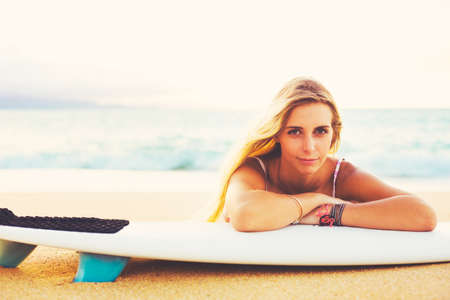 Beautiful Blonde Surfer Girl on the Beach at Sunsetの写真素材