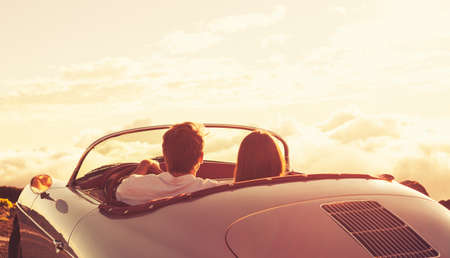 Romantic Young Attractive Couple Watching the Sunset in Classic Vintage Sports Carの写真素材