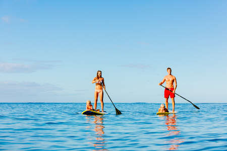 Family Having Fun Stand Up Paddling Together in the Ocean on Beautiful Sunny Morningの写真素材