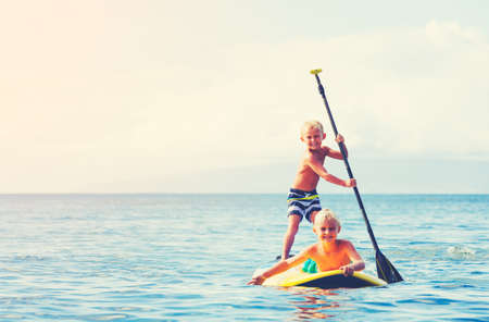 Young Boys Having Fun Stand Up Paddling Together in the Oceanの写真素材