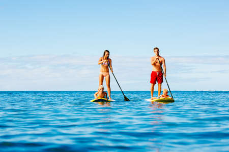 Family Having Fun Stand Up Paddling Together in the Ocean on Beautiful Sunny Morningの写真素材