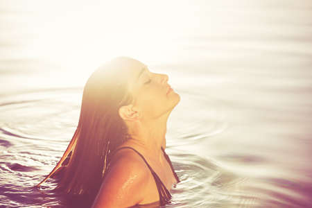Beautiful young woman relaxing in pool at sunset, Luxury resort fashion lifestyleの写真素材