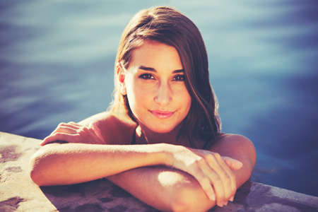 Beautiful young woman relaxing in pool at sunset, Luxury resort fashion lifestyle