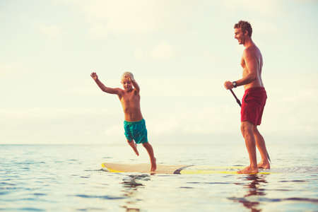 Father and son stand up paddling at sunrise, Summer fun outdoor lifestyleの写真素材