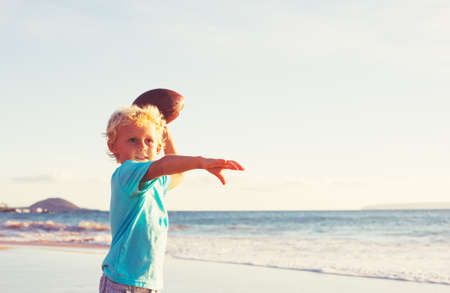 Young Boy Playing Catch Throwing Football on the Beachの写真素材