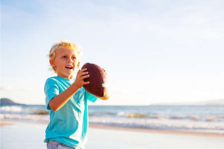 Young Boy Playing Catch Throwing Football on the Beach