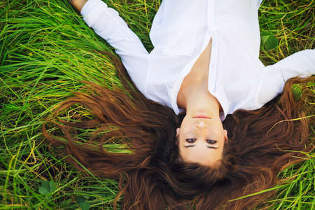 Beautiful Young Woman Relaxing Outdoors in Green Grassの写真素材