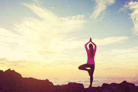 Young Woman Practicing Yoga in the Mountains at Sunset, Healthy Active Lifestyleの写真素材