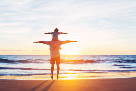 Happy Father and Son Having Fun Playing on the Beach at Sunset. Fatherhood Family Conceptの写真素材