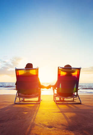 Retirement Vacation Concept, Happy Mature Retired Couple Enjoying Beautiful Sunset at the Beachの写真素材