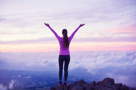 Happy Young Woman Hiker With Open Arms Raised at Sunset on Mountain Peakの写真素材