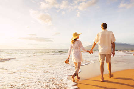 Happy Romantic Middle Aged Couple Enjoying Beautiful Sunset Walk on the Beach. Travel Vacation Retirement Lifestyle Conceptの写真素材