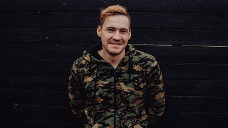 Guy camo, a man in a hoodie on a black wooden background. Soldiers at the wallの写真素材