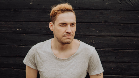 Lucky guy in a white t-shirt. Handsome man on black wall backgroundの写真素材