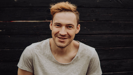 Lucky guy in a white t-shirt. Handsome man on black wall backgroundの写真素材