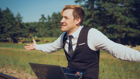 The guy works at a computer in nature on a Sunny clear day. For a laptop on the street, the concept...