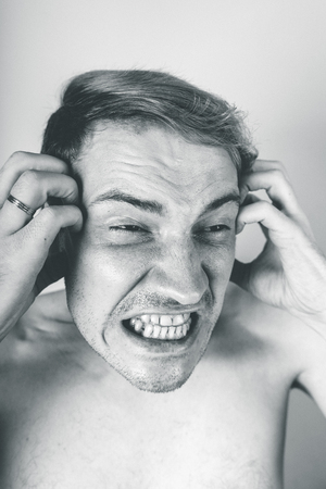 emotional portrait of a crazy guy in closeup. concept: the nervous breakdown, mental disease, headaches and migraine. black and white treatmentの写真素材