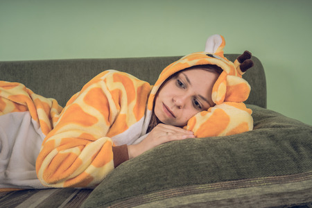 girl in a bright children's pajamas in the form of a kangaroo. emotional portrait of a student. costume presentation of children's animator. Slippers in the form of cat's paws.の写真素材