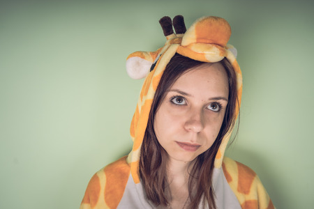 girl in a bright children's pajamas in the form of a kangaroo. emotional portrait of a student. costume presentation of children's animator. Slippers in the form of cat's paws.の写真素材